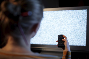 Woman with remote control in front of TV set