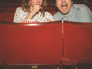 A young couple is watching a scary film in a movie theater