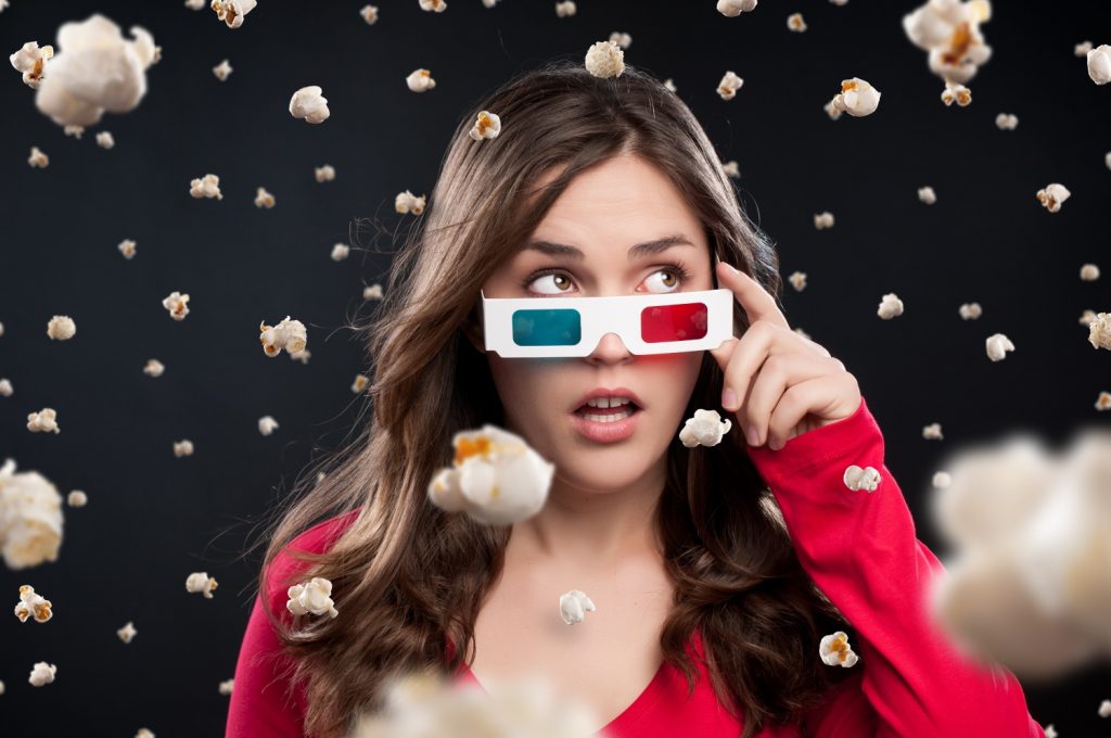 woman wearing 3D TV glasses with popcorn falling down