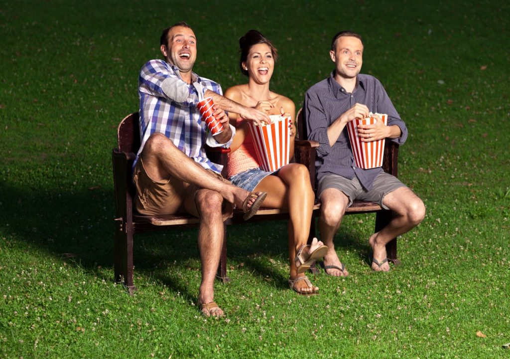 three friends watching a movie at cinema outdoors