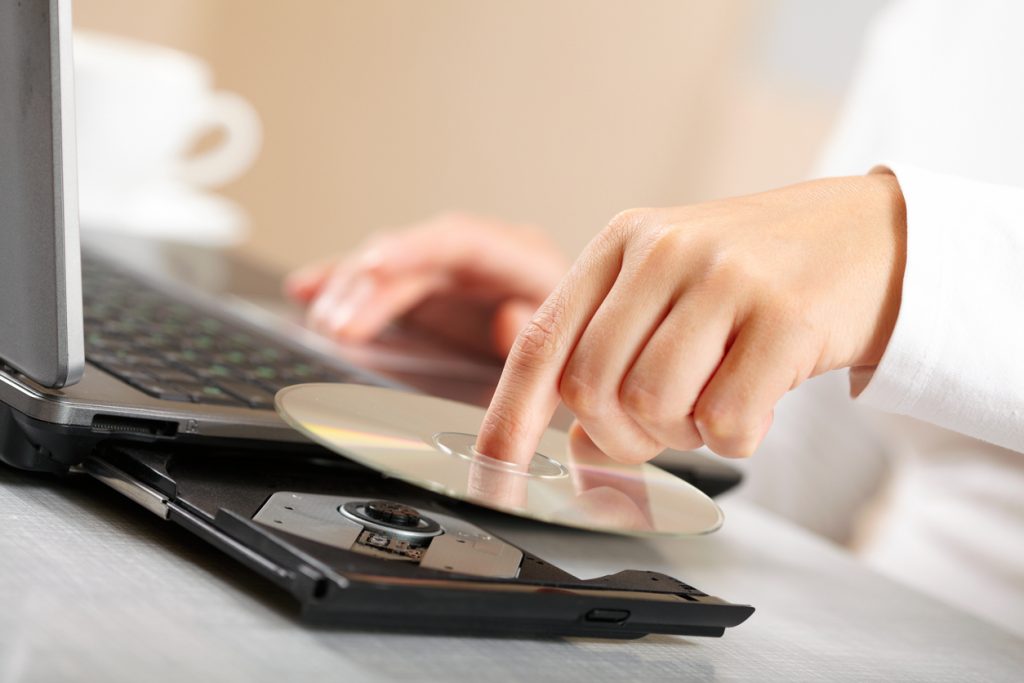 Person Putting a DVD into a Laptop